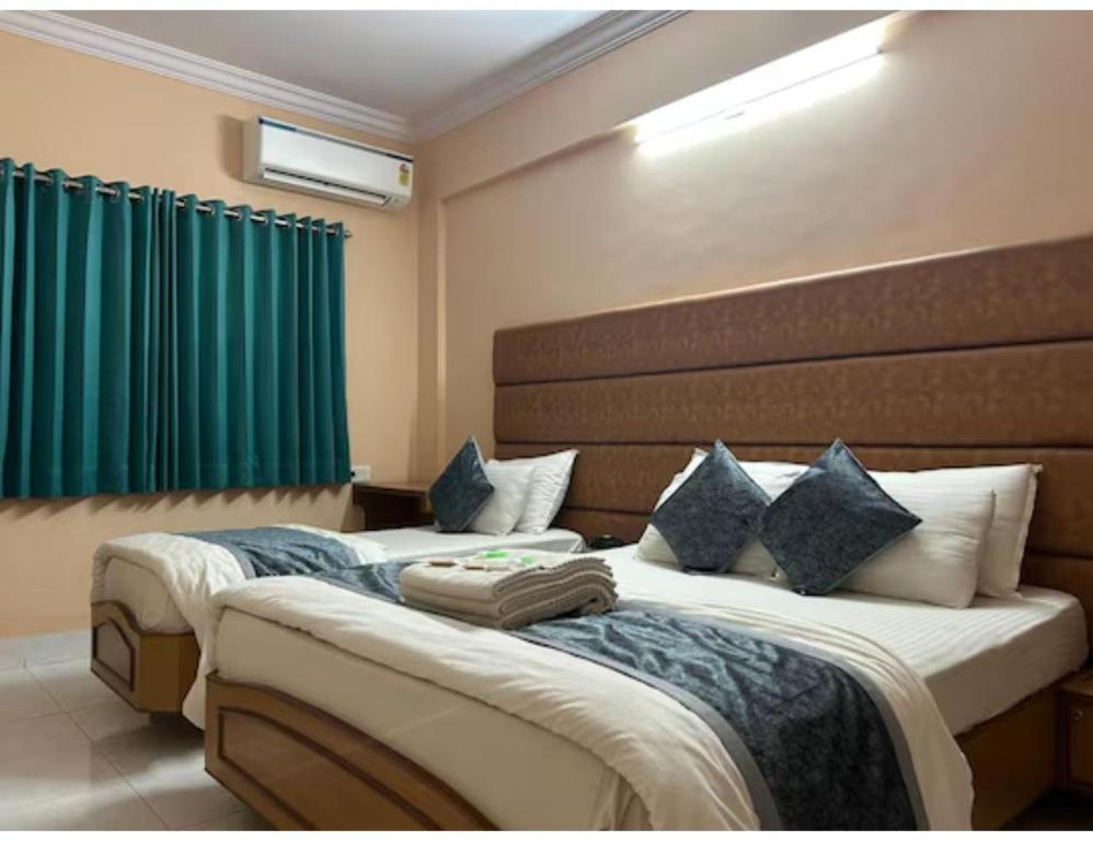 two beds in a hotel room with green curtains at Hotel shree darshan Dwarka in Dwarka