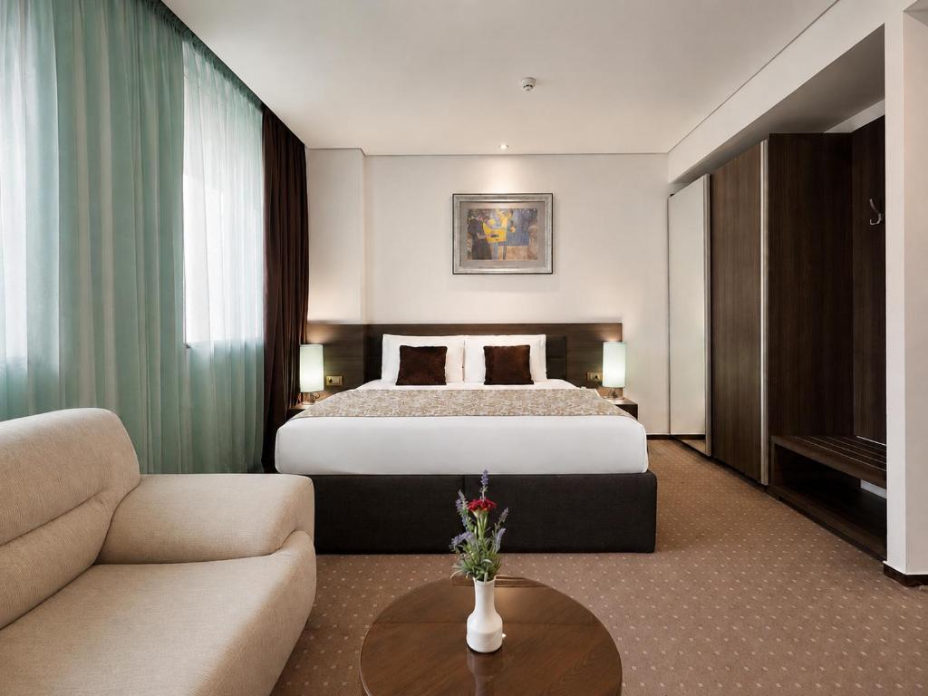a hotel room with a bed and a couch at Hotel Nartel in Prishtinë