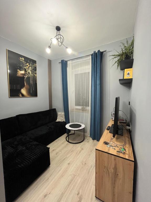 a living room with a black couch and a table at Apartament nad rzeką in Głuszyca