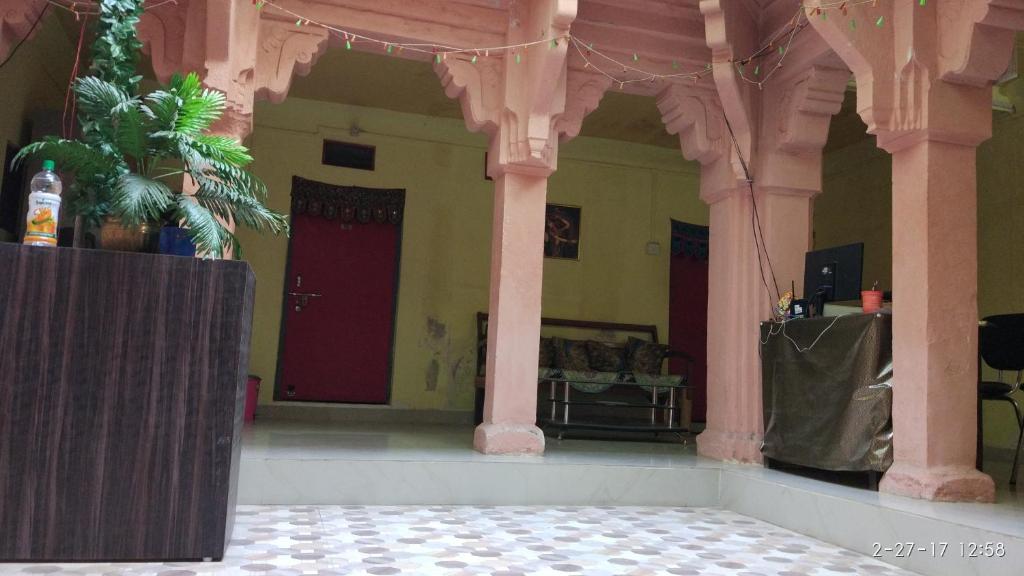 a room with pink columns and a red door at Radha Krishna Home in Varanasi