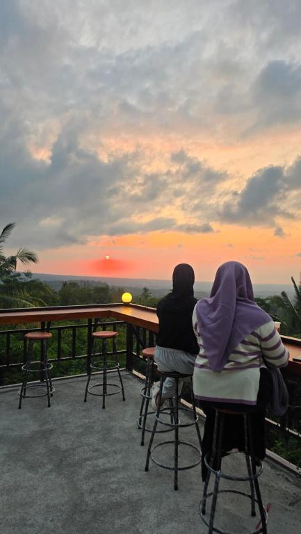 two people sitting at a bar watching the sunset at Bale Sunset Inn in Senaru