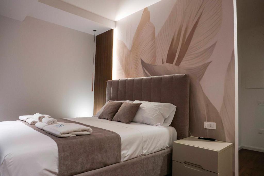 a bedroom with a white bed with a painting on the wall at Tirone Luxury Rooms in Cirò Marina