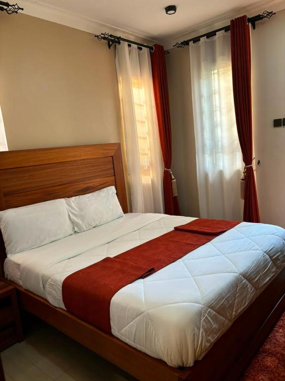 a bedroom with a large bed with red curtains at Armatyr Motel in Kampala