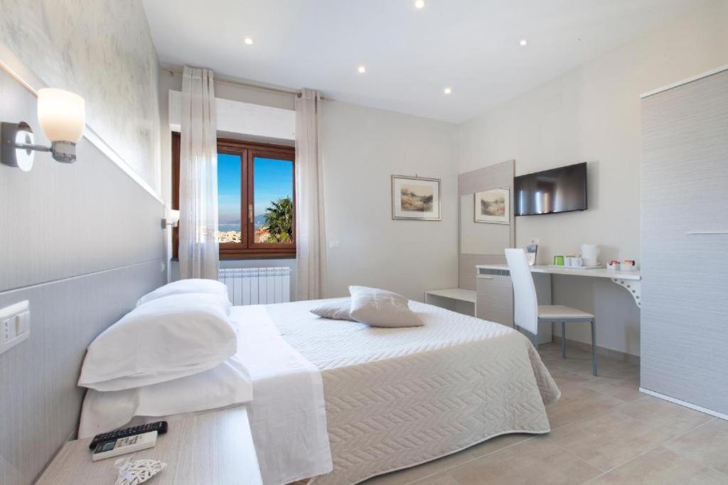 a white bedroom with a bed and a desk at Rooms Sorrento in Sorrento