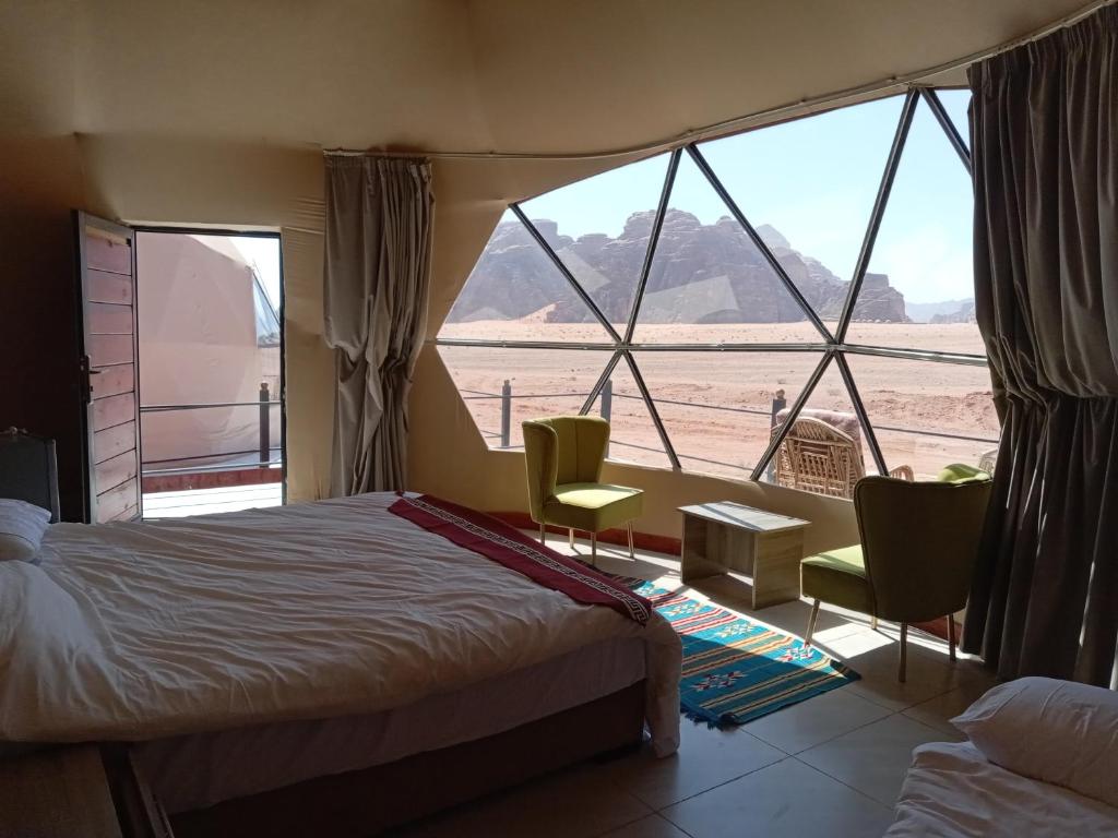 a bedroom with a bed and a view of the desert at Wadi Rum Panorama Suites in Disah