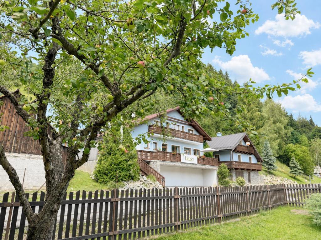 a house behind a fence with a tree at Penzión Liezky in Mýto pod Ďumbierom
