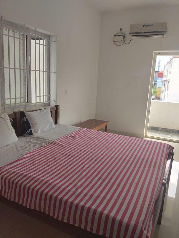 a red and white striped bed in a room at Meenatchi Hotel and Residency in Alāndurai