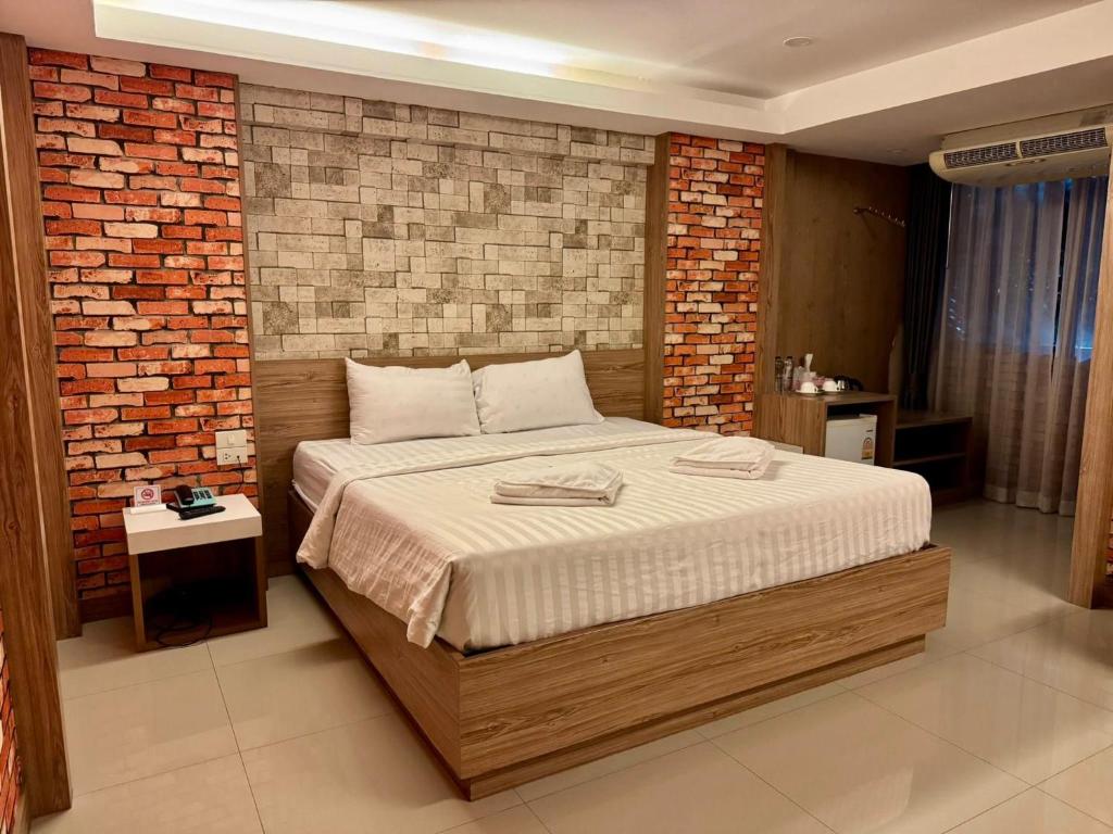 a bedroom with a large bed with a brick wall at Nava Grand in Ban Talat Rangsit