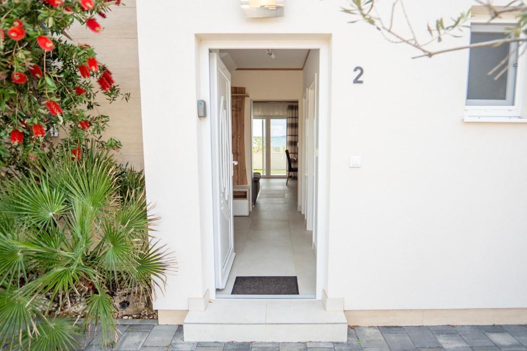 a hallway of a house with a white door and flowers at Beachfront Reiterer Villa V2 with Seaview 30 meters from the Beach - CROWONDER LUXURY RENT in Privlaka
