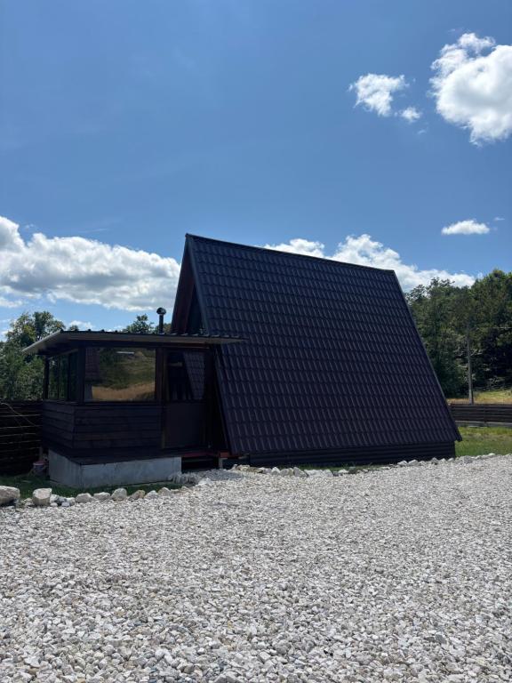 a house with a black roof on a pile of gravel at RanyA-Frame in Nucşoara
