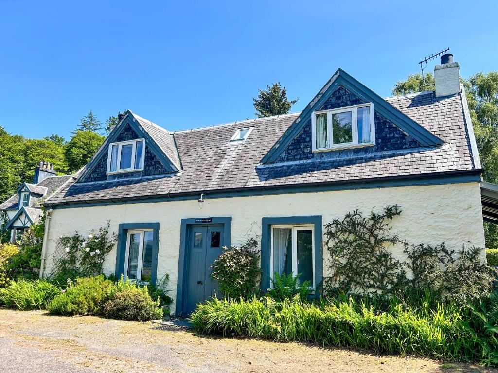 a white house with a blue door and windows at Darroch Beag in Saint Catherines