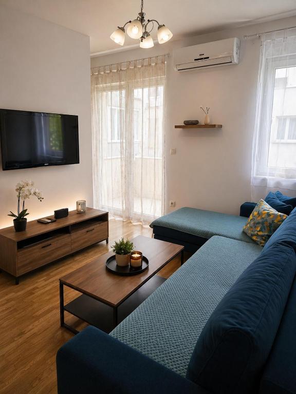 a living room with two blue couches and a tv at Apartment Gonzales in Mostar