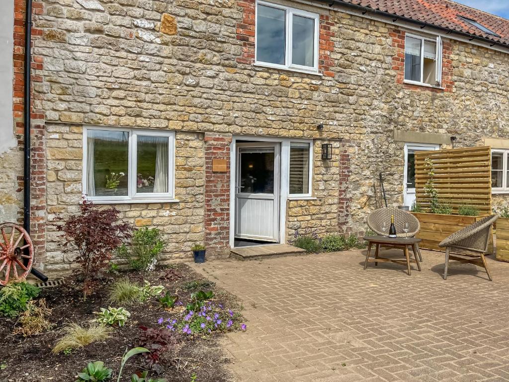 a stone house with a patio and a wooden bench at The Cartshed - Uk50426 in Malton