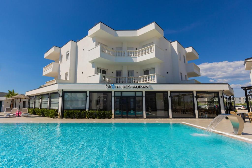 a hotel with a swimming pool in front of a building at Sirena Garden Resort in Tale