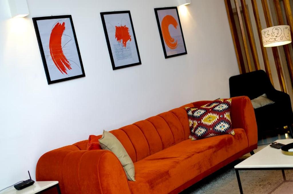 an orange couch in a living room with pictures on the wall at Tipson Apartments in Bamgbose