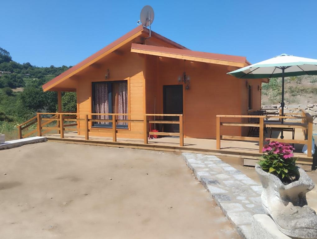 a small house with a patio and an umbrella at Casa dos Cortinhais 2 in Oliveira de Frades