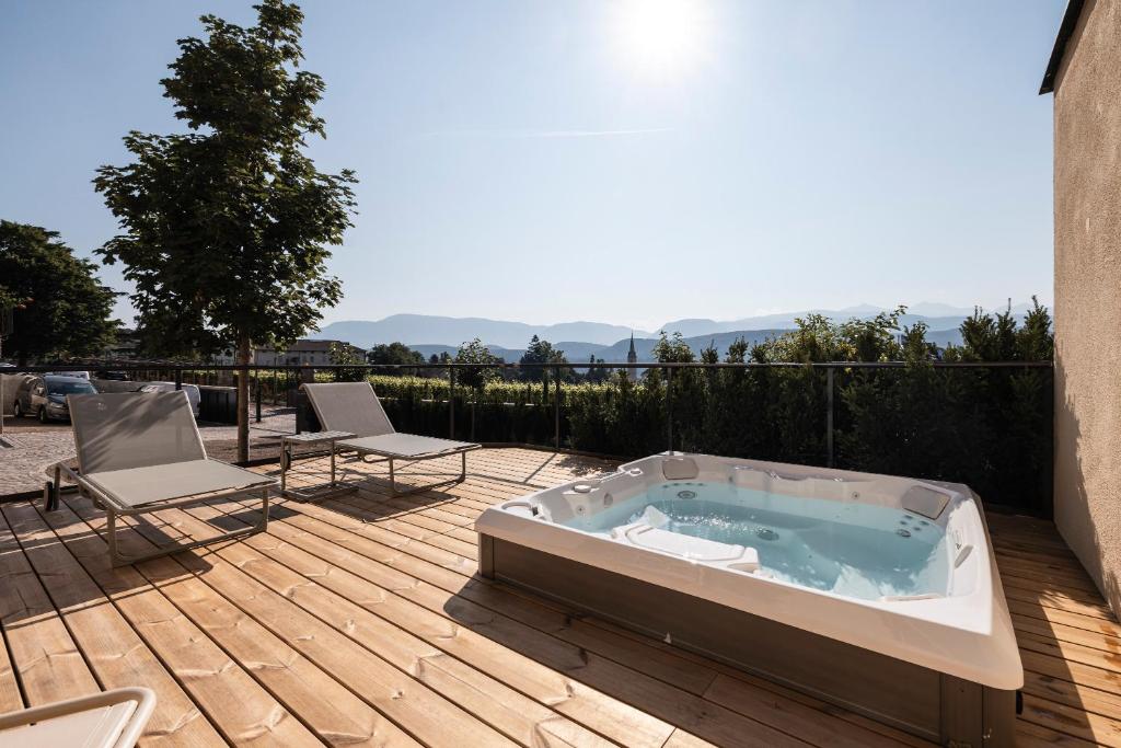 a hot tub sitting on a deck with two chairs at Essa Rooms NEW in Caldaro
