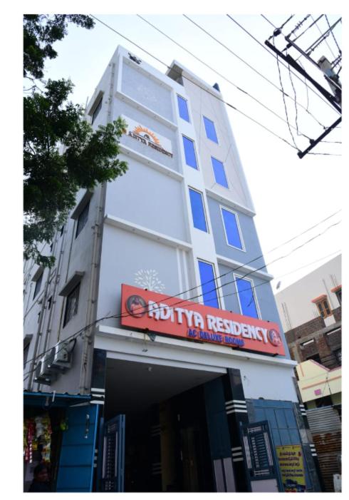 a tall white building with a red sign on it at Aditya Residency in Mādhavaram