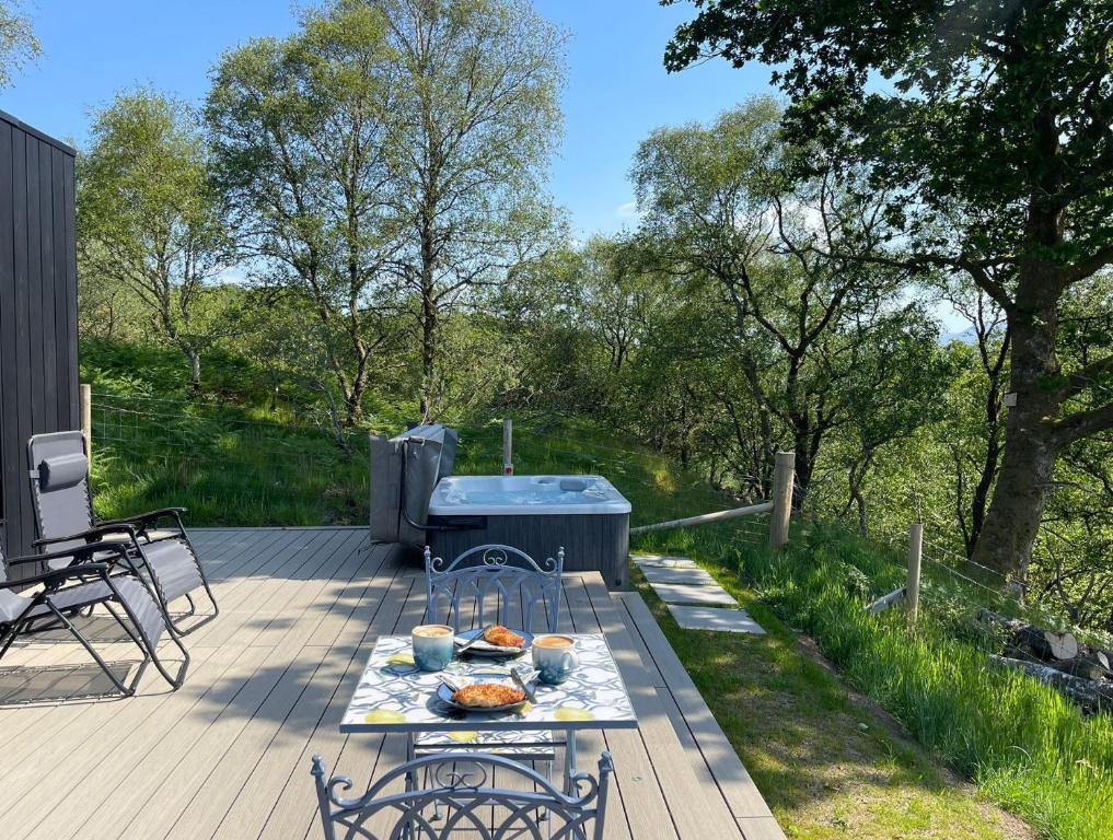 a picnic table on a deck with a hot tub at Cadderlie Cabin - Luxury Woodland Escape with Hot Tub Near Oban in Oban