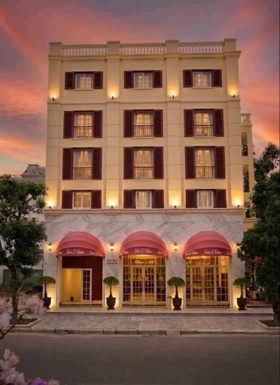 a large white building with windows and a sunset at Hotel L Odeon Phu My Hung in Ho Chi Minh City