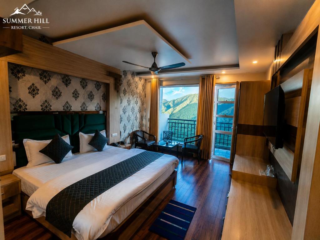 a bedroom with a large bed and a large window at Summer Hill Resort in Chail