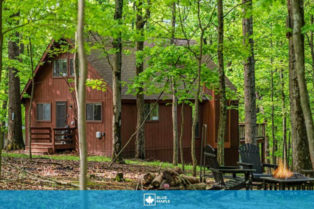 a red cabin in the woods next to a forest at DogFriendly wHot Tub Fire Pit Resort Access in Hedgesville