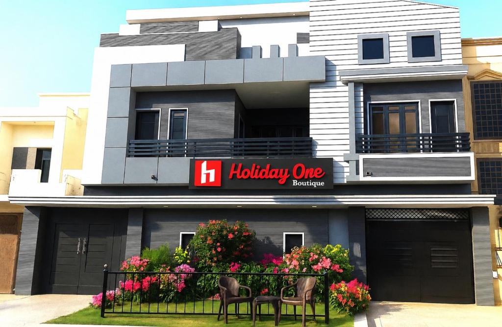 a building with two chairs and flowers in front of it at Holiday One Hotel & Suites - Expo Center in Karachi
