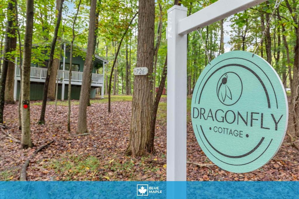 a sign for a dragonfly cottage in the woods at Fireplace, Fire Pit & Resort Amenities in Hedgesville