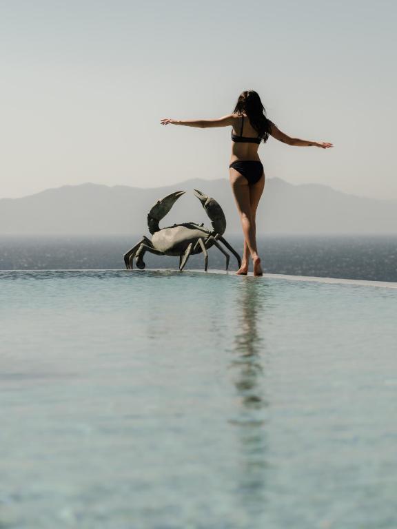 a woman in a bikini standing next to two birds at Tropicana Suites & Villas Mykonos in Paradise Beach