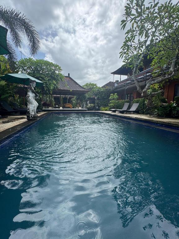a swimming pool with a statue in front of a house at GB Ubud in Kubupenlokan