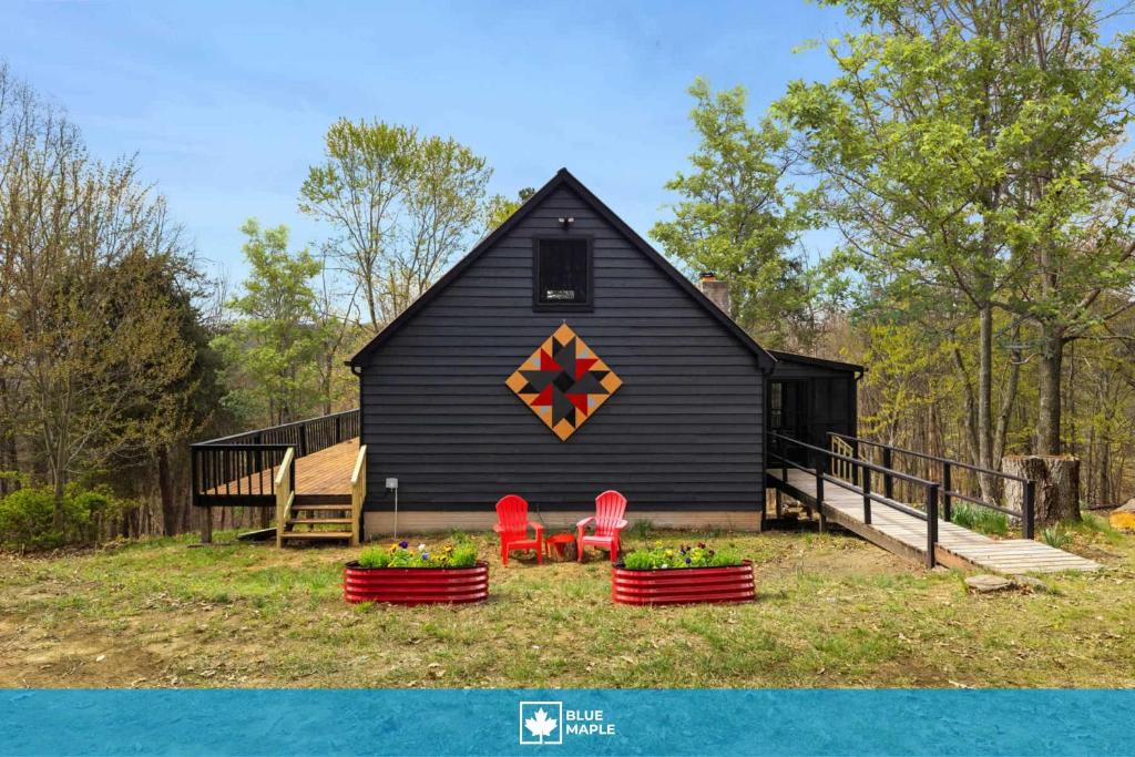 a black barn with two red chairs in front of it at Cozy cabin w grill deck & game room in Mathias
