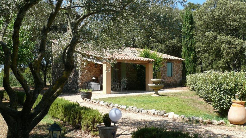 un jardin avec une maison en pierre avec un arbre dans l'établissement Les Bastides de l'Auviduery, à Moissac-Bellevue