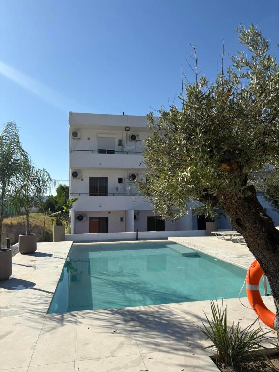 a building with a swimming pool in front of a building at Nikos BnB in Faliraki