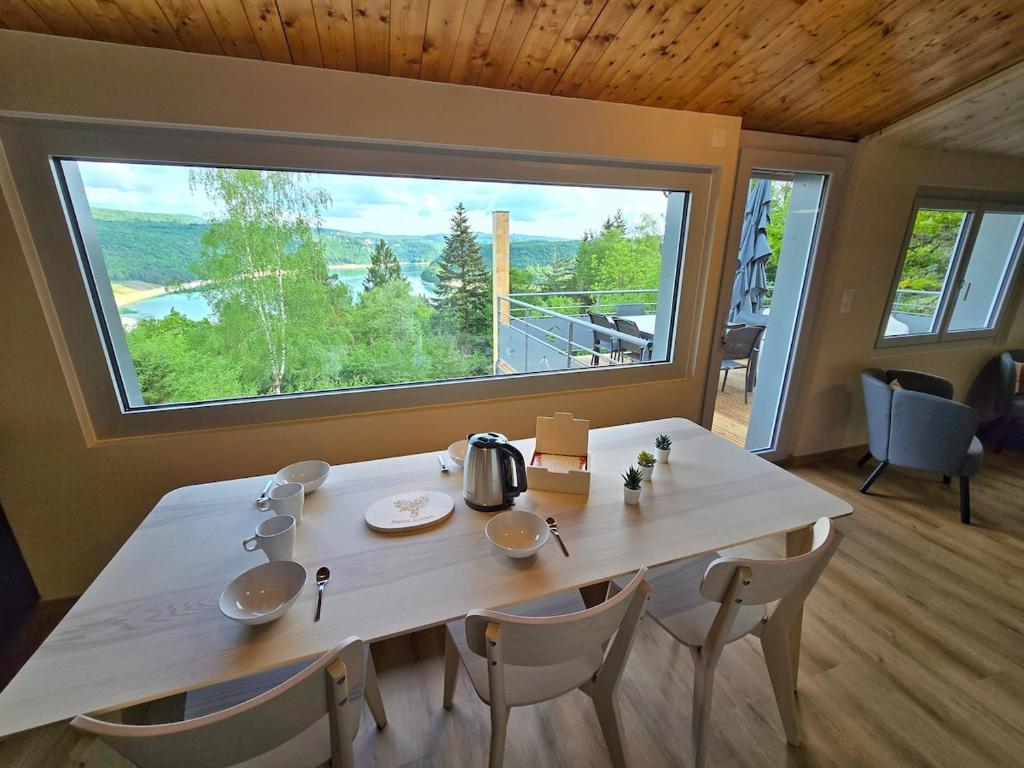 a dining room table with chairs and a large window at Les Reflets Bleus in Maisod