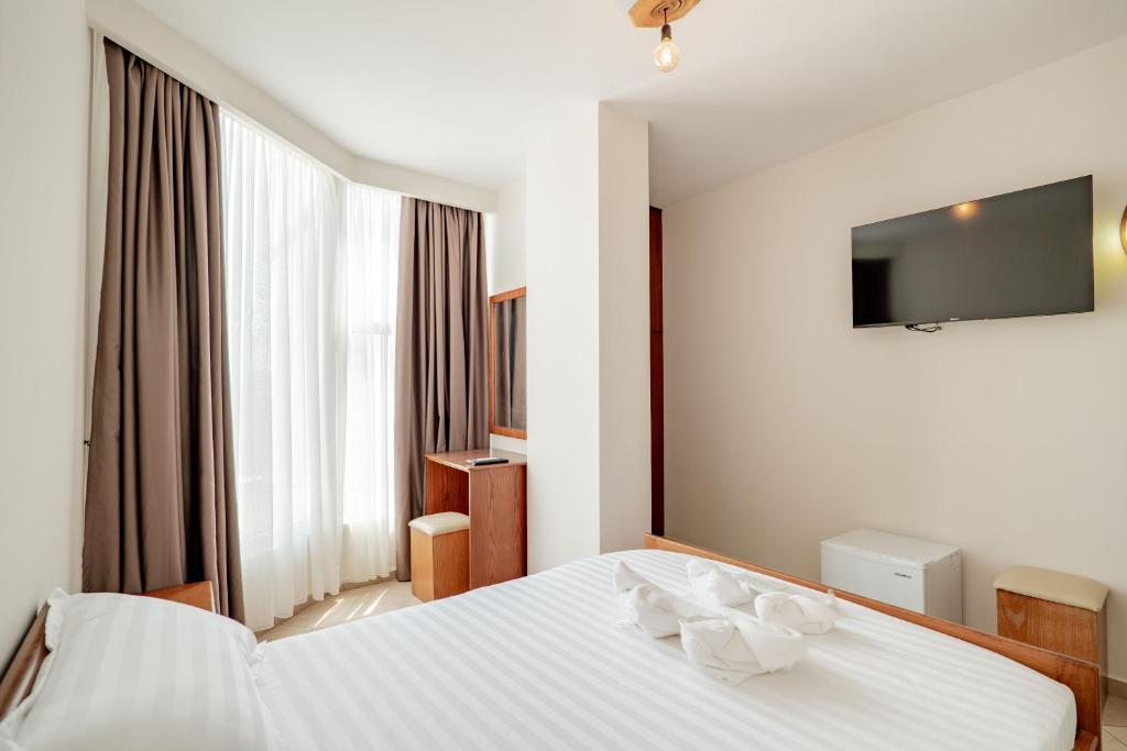 a bedroom with a white bed with a flat screen tv at Hotel Boutique Vioalv in Sarandë