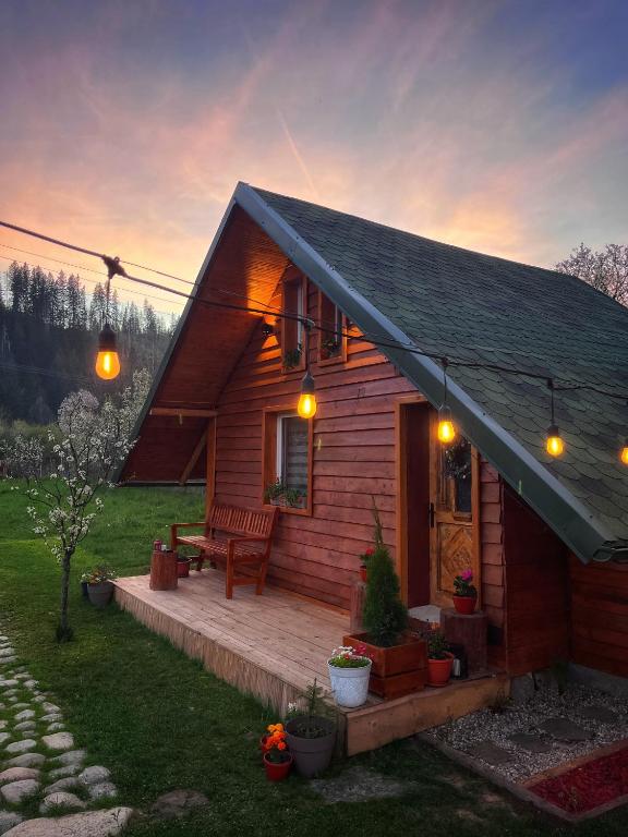 a small wooden house with a porch and a bench at EscapeTinyCabin by IezerVenture in Lereşti