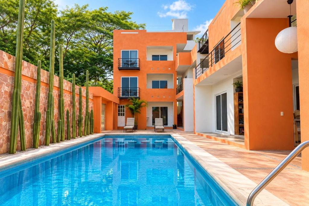 an apartment with a swimming pool in front of a building at La Aurora Puerto Escondido in Puerto Escondido