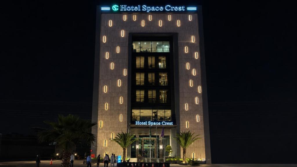 a tall building with a sign on it at night at Hotel Space Crest in Faisalabad