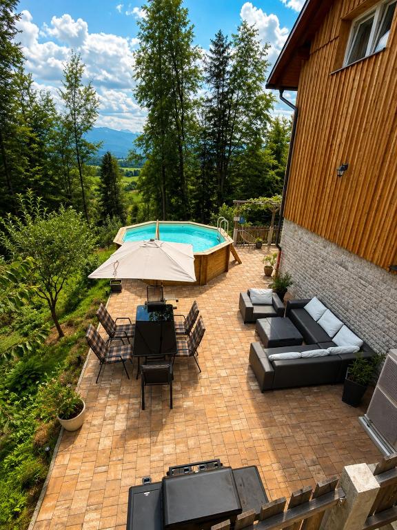 a patio with an umbrella and chairs and a pool at Apartment A&A in Niederdorf