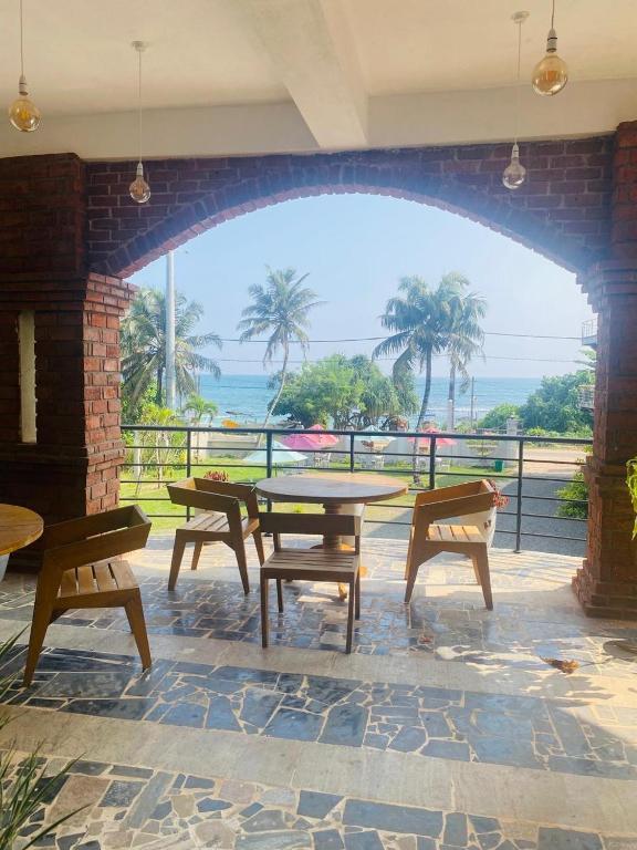 a patio with tables and benches and a view of the ocean at Lushy Glorious Hotel in Matara