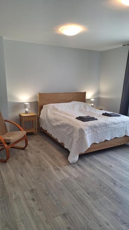 a bedroom with a large bed and a chair at Petite Haven in Grobiņa