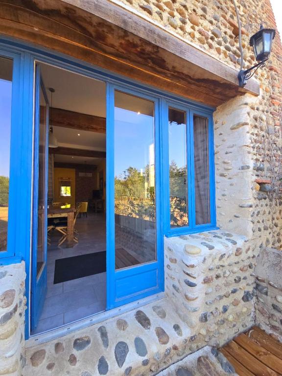 a house with blue windows and a patio at La parenthèse de Saint Esselin 2 in Larreule