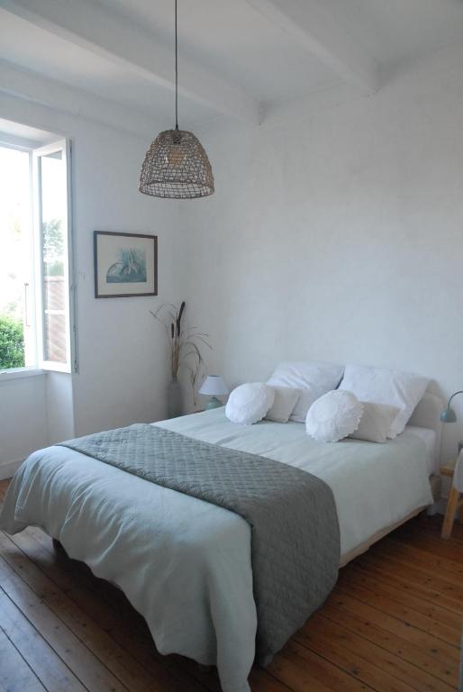a white bedroom with a large bed with a pendant at la colombe du marais in Courçon