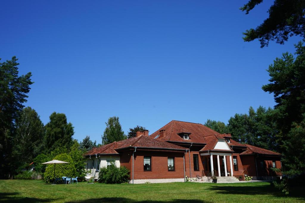 a red brick house on a green lawn at Thula - Apartment in Villa Ambrosian in Trzebież