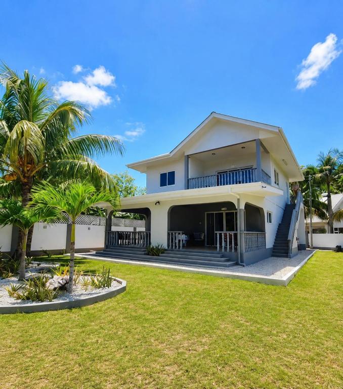 a large white house with palm trees in the yard at Trwa Koko Self-catering in Grand'Anse Praslin