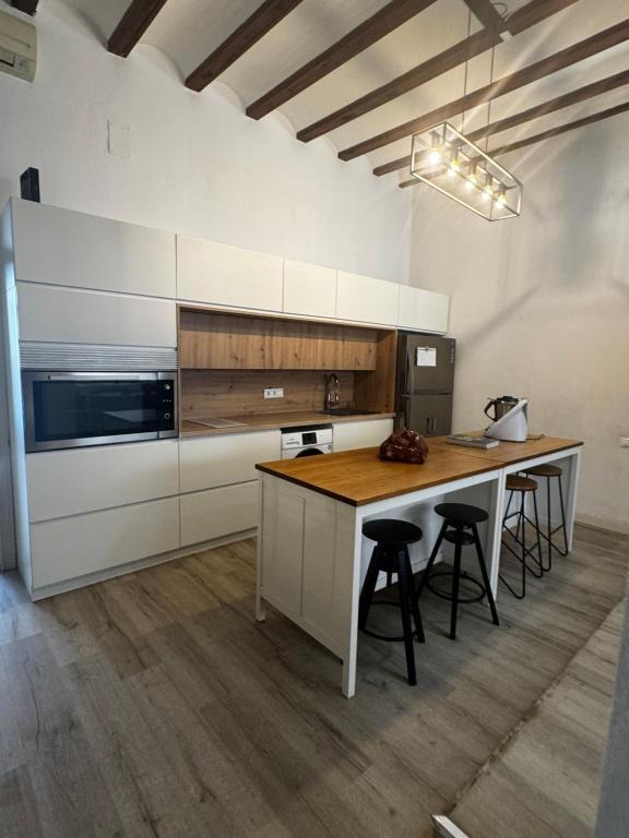 a kitchen with white cabinets and a table with stools at Casa Capereta in Alberique