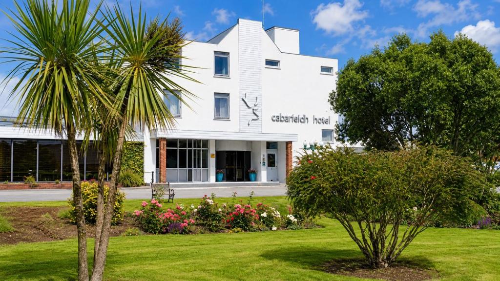 a white house with a palm tree in the yard at Cabarfeidh Hotel in Stornoway