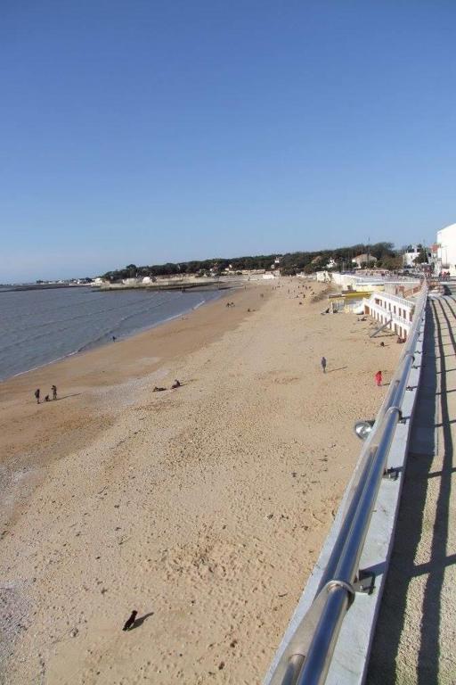 a beach with people on it and the ocean at Hôtel Le Galet Bleu in Fouras