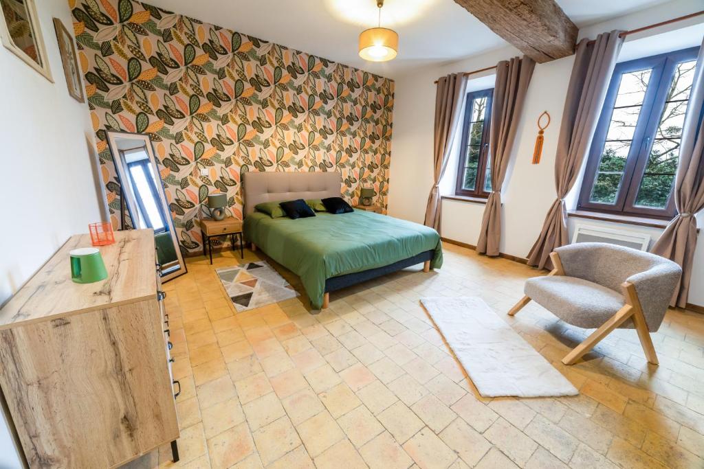 a bedroom with a bed and a chair and windows at L Ancestral in Beaumont-les-Autels