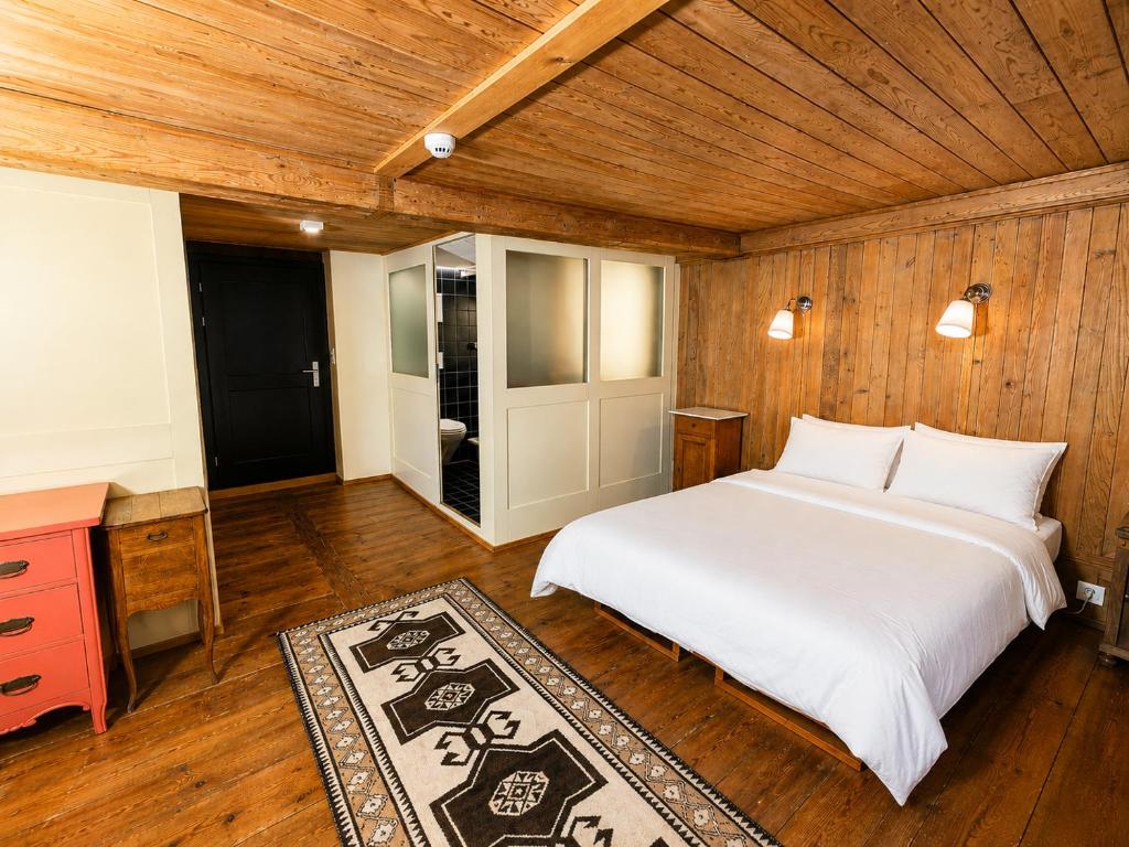 a bedroom with a white bed and a wooden ceiling at Klösterli Malters in Malters